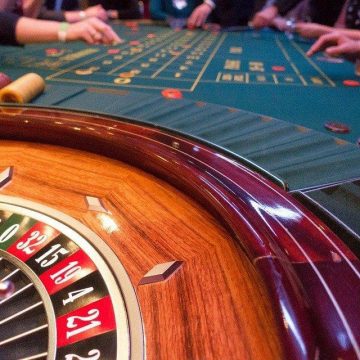 Players at the Roulette table with the Roulette wheel in the background