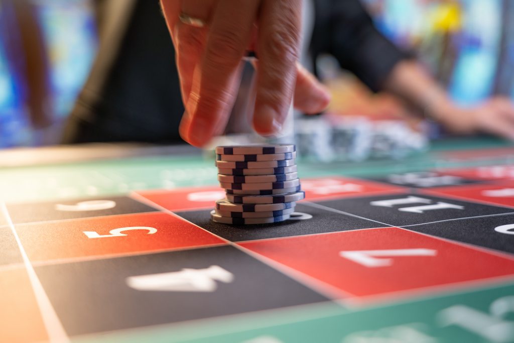 A person placing game chips on a Roulette table 