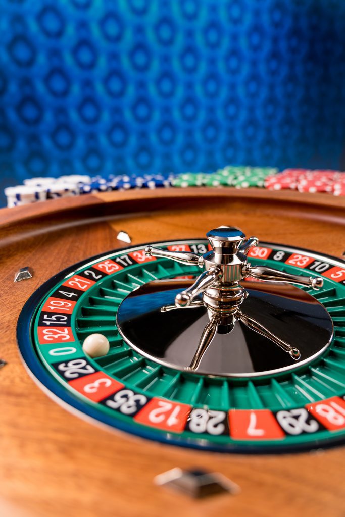 Roulette Wheel with Betting Chips In the Background.
